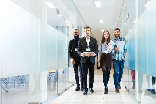 Full length of group of happy young business people walking the corridor in office together.jpeg